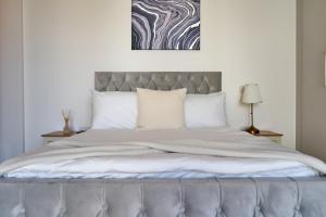una camera da letto con un grande letto con cuscini bianchi di Luxury Stylish 2 Beds / 2 Baths a Londra