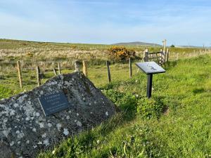 a sign next to a rock in a field at Penrallt-Fach Traditional Welsh cottage Pembrokeshire in Mynachlogddu