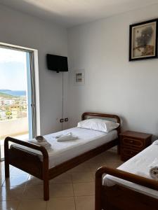 a bedroom with two beds and a tv on the wall at Esmeralda Hotel & Restaurant in Ksamil