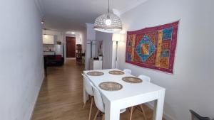 einen weißen Esstisch mit Stühlen und ein Gemälde an der Wand in der Unterkunft Céntrico Apartamento en Ronda in Ronda