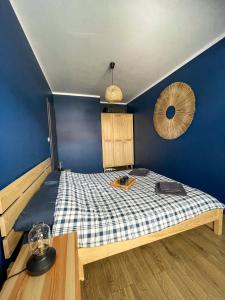 une chambre avec un lit avec un mur bleu dans l'établissement Apartament Cień Wiatru, à Darłowo