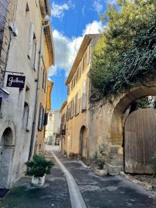 an alley in a city with an archway and buildings at Le Lourmarinois in Lourmarin