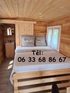 uma cama grande num chalé de madeira com em Tiny House Roulotte em Cuges-les-Pins
