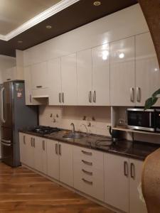 uma cozinha com armários brancos, um lavatório e um frigorífico em Апартаменти ''Комфорт'' em Kamianets-Podilskyi