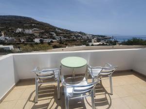 una mesa y sillas en un balcón con vistas en Galini Apartments Sikinos Travel en Síkinos