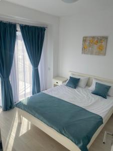 1 dormitorio con 1 cama grande y cortinas azules en Apartament Oana, en Băile Felix