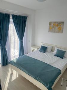 バイレ・フェリクスにあるApartament Oanaのベッドルーム1室(青いカーテン付きの大型ベッド1台付)