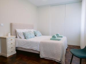 a bedroom with a white bed and a blue chair at Pontes Guest House in Arcozelo
