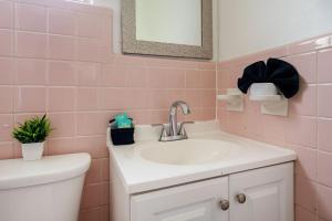 Baño rosa con lavabo y aseo en Holiday Retreat Detroit Ford Flat Rock Assembly, en Woodhaven