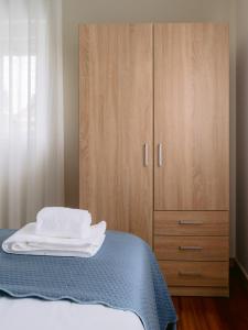 a bedroom with a bed and a wooden cabinet at Pontes Guest House in Arcozelo