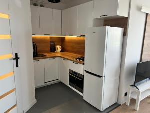 a kitchen with white cabinets and a white refrigerator at Apartament Zbożowa in Toruń