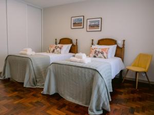 a room with two beds and a chair at Pontes Guest House in Arcozelo