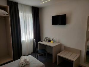 ein Hotelzimmer mit einem Schreibtisch und einem TV an der Wand in der Unterkunft IL VITIGNO in Dossobuono