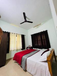 Schlafzimmer mit einem Bett und einem Deckenventilator in der Unterkunft Ocean Pearl in Kozhikode
