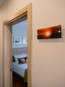 a door to a bedroom with a bed and a painting at Pontes Guest House in Arcozelo