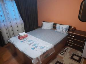 a small bedroom with a bed and a dresser at Casa G in Douăzeci şi Trei August +1 photo
