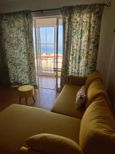 een woonkamer met een bank en uitzicht op de oceaan bij Apartamento Girassol in Luz