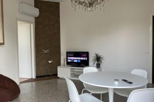 comedor blanco con mesa y TV en la casa di Antoine, en Cesano Maderno