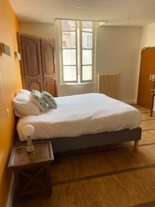 un grande letto in una stanza con tavolo di Hôtel des Cymaises a Semur-en-Auxois