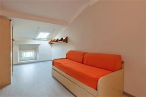 an orange couch in a white room with a window at [- Poetic Seafront Penthouse Versilia -] in Massa