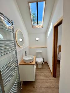 a bathroom with a toilet and a sink and a window at Stunning stone coach house in Marple