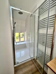 a glass shower in a bathroom with a window at Stunning stone coach house in Marple