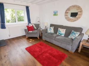 uma sala de estar com um sofá, uma cadeira e um tapete vermelho em The Duck House em Treffgarne