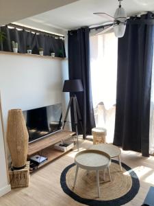 een woonkamer met 2 tafels en een tv bij Tournamy Les Olivier in Mougins