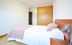 1 dormitorio con cama blanca y cabecero de madera en Céntrico apartamento con parking en Cambados, en Cambados
