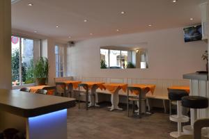 un restaurante con un bar con sillas naranjas y espejo en Hotel St. Gervais, en Ginebra