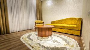 a living room with a table and a yellow couch at Hotel Bankir Khiva in Khiva