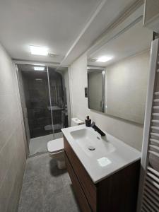 a bathroom with a sink and a toilet and a mirror at El txoko de onso in Santibáñez de la Peña