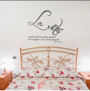 sypialnia z łóżkiem z napisem na ścianie w obiekcie Casa vacanze Mimí w Cefalù