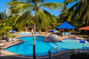 a resort pool with palm trees and people swimming at Orange Praia Hotel in Itamaracá