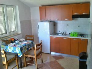 a kitchen with a table and a white refrigerator at Apartments Cajic in Povile