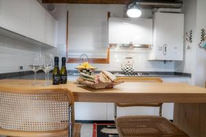 una cocina con una mesa de madera con sillas y copas de vino en Alilandia - Casa Vacanza, en Valdobbiadene