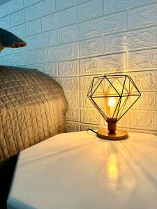 a lamp sitting on a table next to a bed at Apto Loft Novo - Porto Belo - 5 min a pé da praia in Porto Belo