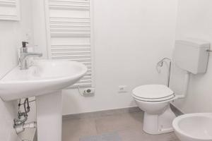 a white bathroom with a toilet and a sink at Staurenghi Green Apartment in Varese