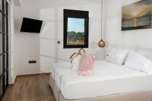 a white bedroom with a white bed and a window at OLIVOMARE in Kyparissia