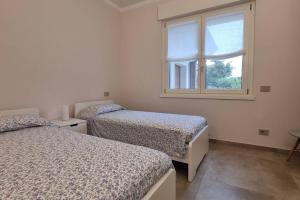 Duas camas num quarto branco com uma janela em Villa Katy em Tormine