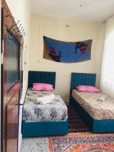two beds in a room with pink and blue at Rosa Hostel in Mardin
