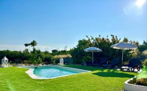 a swimming pool in a yard with chairs and umbrellas at Trullo Oasi Veronica in Ostuni