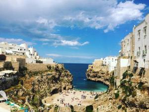 a group of people sitting on a beach next to the ocean at Casa d'aMare Polignano a mare in Polignano a Mare