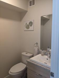 a bathroom with a toilet and a sink and a mirror at Elmwood stay in Winnipeg