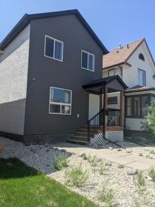 a home with a black house with a porch at Elmwood stay in Winnipeg