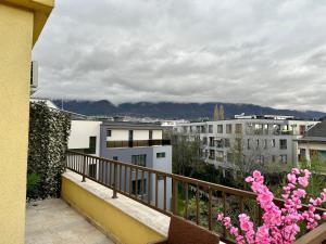 un balcón con flores rosas, edificios y montañas en Vitosha Terrace 1BR Apartment with Parking, en Sofía