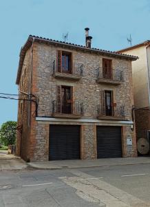 a brick building with two garage doors on a street at Cal Genís de Montmajor - WIFI in Montmajor
