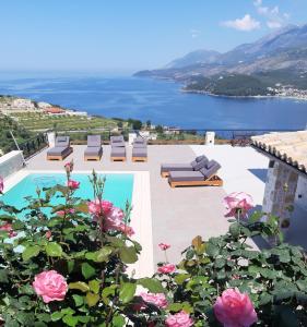 a pool with a view of the water and flowers at Argileos Rooms in Himare