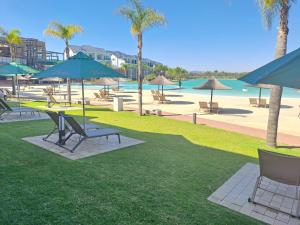 a park with chairs and umbrellas and a beach at THE BLYDE Holiday Apartments in Pretoria