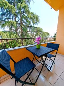a table and chairs on a balcony with a vase of flowers at Apartman Koli Opatija in Opatija